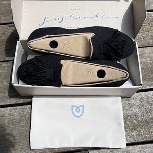 Rothy’s black knitted flats with beige outline and frill detail at top